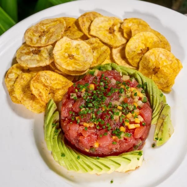 Tuna tartare with avocado slices and plantain chips on a white plate at Tiki Fish n Burgers.
