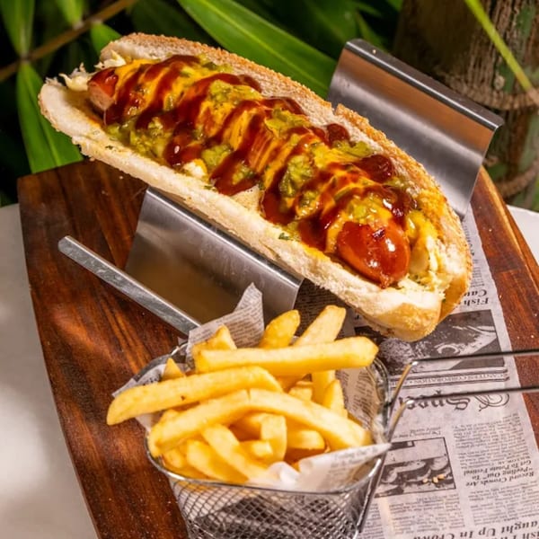 A hot dog with cheese, relish, and ketchup, served with a side of french fries.