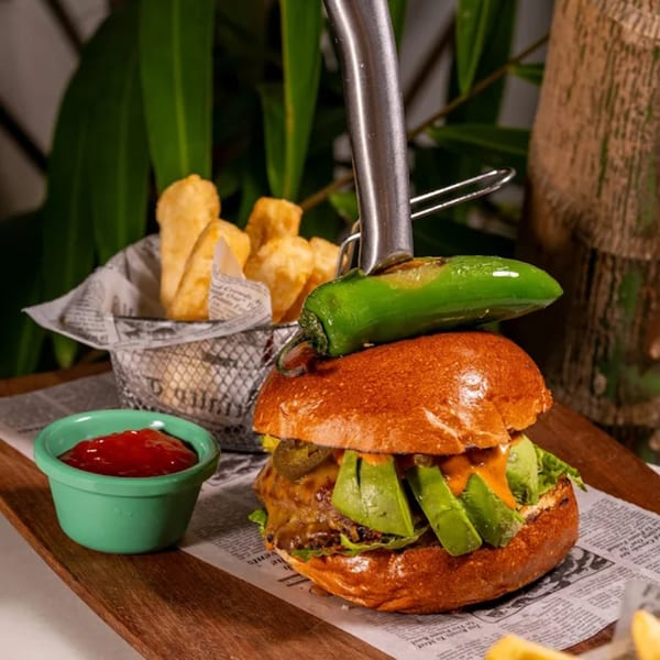 A Tiki Fish n Burgers avocado burger with a jalapeño on top, fries, and ketchup.