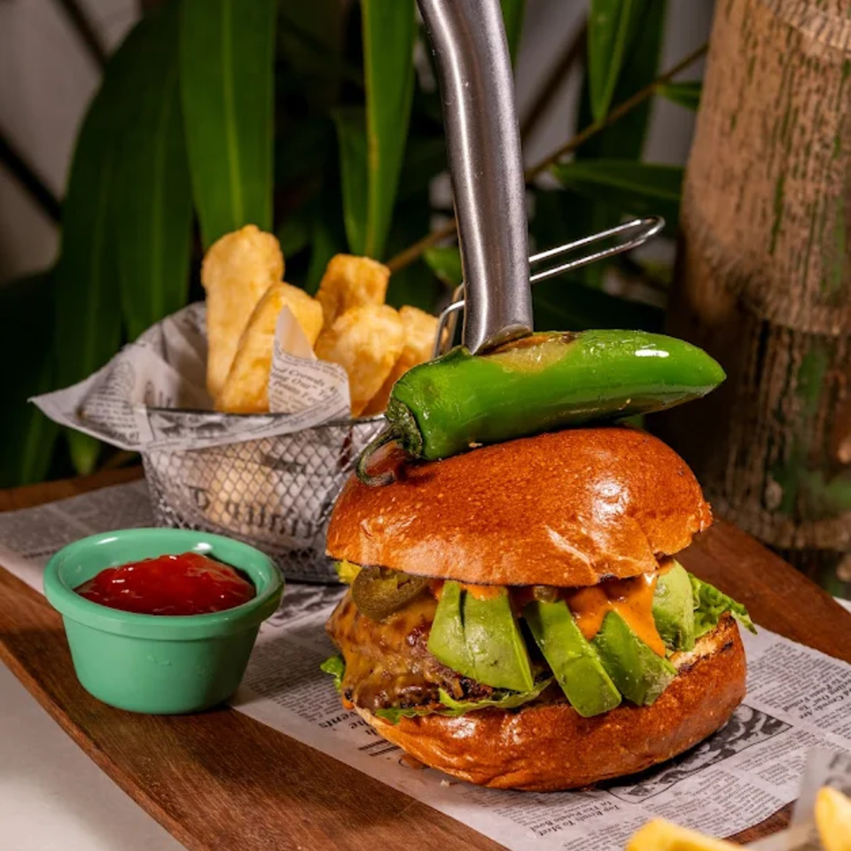 A Tiki Fish n Burgers avocado burger with a jalapeño on top, fries, and ketchup.