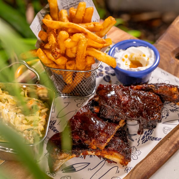 Tiki Fish n Burgers' BBQ ribs, fries in a metal basket, coleslaw, and dipping sauce.