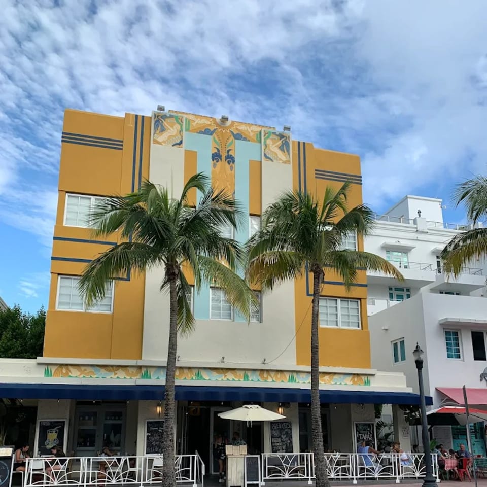 Tiki Fish n Burgers restaurant with a yellow and blue Art Deco facade and palm trees.