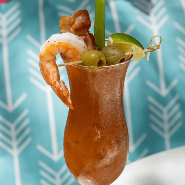 A Tiki Fish n Burgers Bloody Mary cocktail garnished with shrimp, bacon, olives, lime, and celery.
